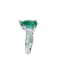 This teardrop emerald ring displays its left side profile from the top to down band view.
