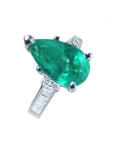 Emerald ring with diamond accents on top left side position view.