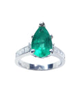 A teardrop colombian emerald ring crafted in 14k white gold with accent princess cut diamonds on the band.