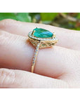 The topside and underside view of a teardrop emerald ring on a person's finger.