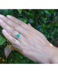 1.39 ct. teardrop emerald halo ring with diamonds on a 14K white gold band, worn on a hand.