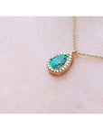 Pear-shaped natural emerald necklace with diamond halo on 14K yellow gold chain.
