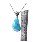 Vivid blue and white teardrop larimar pendant on a sterling silver necklace, next to a ruler.