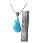 Vivid blue and white teardrop larimar pendant on a sterling silver necklace, next to a ruler.