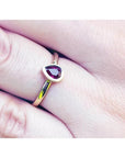 Woman's hand wearing a 14K yellow gold ring with a teardrop natural ruby solitaire.