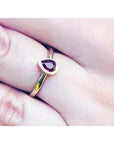 Woman's hand wearing a 14K yellow gold ring with a teardrop natural ruby solitaire.