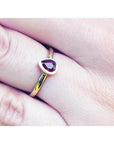 Woman's hand wearing a 14K yellow gold ring with a teardrop natural ruby solitaire.
