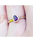 Woman's hand wearing a 14K yellow gold ring with a bezel-set teardrop natural ruby solitaire.