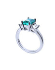 18K white gold three-stone ring with a rectangular emerald and two baguette diamonds.