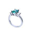 18K white gold three-stone ring with a rectangular emerald and two baguette diamonds.