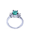 Lateral profile top and gallery view of a natural emerald three stone ring and two diamonds on a white background.
