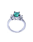 Emerald cut three stone ring with medium bluish green emerald and side baguette diamonds in 18K white gold.