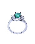 Emerald cut three stone ring with medium bluish green emerald and side baguette diamonds in 18K white gold.