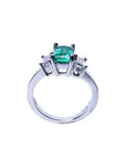 Emerald cut three stone ring with medium bluish green emerald and side baguette diamonds in 18K white gold.