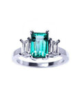A colombian emerald three stone ring with side baguette natural diamonds, crafted in 18 white gold.