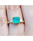 18K yellow gold three-stone ring with a square Colombian emerald and princess-cut side diamonds.