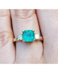 18K yellow gold three-stone ring with a square Colombian emerald and princess-cut side diamonds.