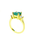 18K yellow gold three-stone ring with a square emerald and princess-cut side diamonds.