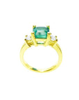 18K yellow gold three-stone ring with a square emerald and princess-cut side diamonds.