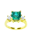 This Emerald-cut three stone emerald ring for women has side princess cut natural diamonds and made of 18k gold.