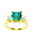 This Emerald-cut three stone emerald ring for women has side princess cut natural diamonds and made of 18k gold.