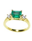 A yellow gold emerald ring east west design with side natural diamonds.