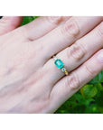 1.01 ct rectangular emerald ring with natural diamond accents set in 14K yellow gold on a hand.