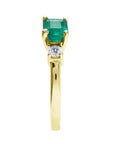 The side profile view of this three stone emerald ring displays the top and the band design.