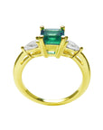 Gold ring with a natural emerald and side diamond, top and lateral profile visibles.