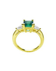 14K yellow gold three-stone ring with a vibrant emerald and two pear-shaped diamonds.