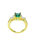 14K yellow gold three-stone ring with a vibrant emerald and two pear-shaped diamonds.