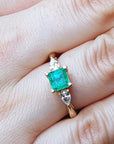 Emerald and diamond ring on a hand