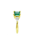 14K yellow gold three-stone ring with a vibrant emerald and two pear-shaped diamonds.