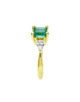 14K yellow gold three-stone ring with a vibrant emerald and two pear-shaped diamonds.