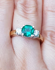 Bridal's May birthstone ring three stone round cut on a finger.
