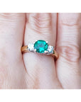 Bridal's May birthstone ring three stone round cut on a finger.