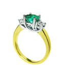 A 14k yellow gold emerald three stone ring and diamond accents on a white background.