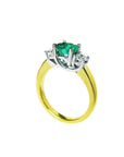 A 14k yellow gold emerald three stone ring and diamond accents on a white background.