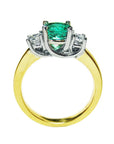 Lucida style emerald three stone ring and diamond accents on a white background.