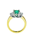 Lucida style emerald three stone ring and diamond accents on a white background.