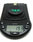 Three stone natural loose emeralds set square, on a digital scale for weight