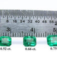 Three emerald-cut natural green emeralds, 0.52, 0.66, and 0.75 carat, displayed with a ruler.
