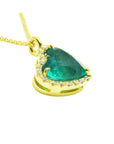 Tilted heart emerald necklace with halo diamonds in 18K yellow gold.