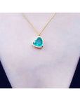 Tilted heart emerald necklace with halo diamonds on an 18K yellow gold chain.