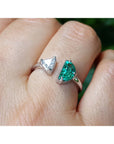 This women's negative space Toi et Moi ring features a natural Colombian emerald and a trillion-cut diamond, handcrafted in 18k solid white gold.