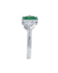 The emerald showcases fine quality with its distinctive fancy cut, while the geometric trillion diamond creates striking visual contrast.