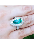 Anillo de oro blanco 14k con esmeralda colombiana corte pera 3.35 ct y halo de diamantes.