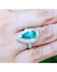 Anillo de oro blanco 14k con esmeralda colombiana corte pera 3.35 ct y halo de diamantes.