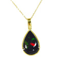 Teardrop-shaped Wello black opal pendant on a gold chain on topside view against a white background