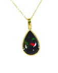 Teardrop-shaped Wello black opal pendant on a gold chain on topside view against a white background